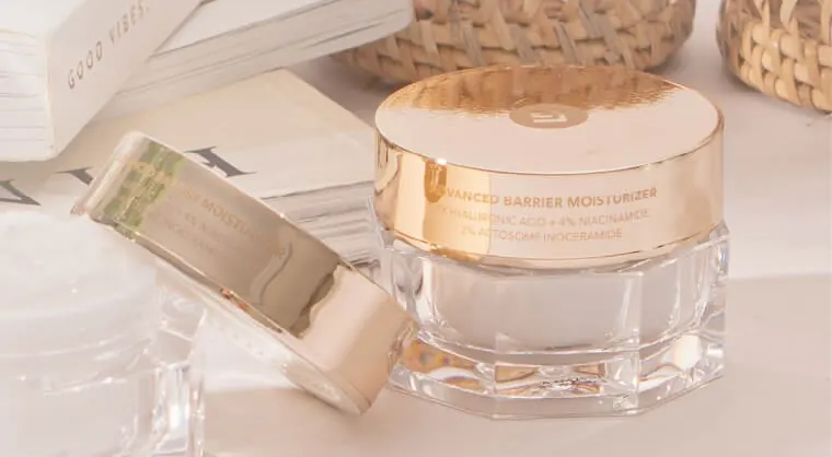 Jar Advanced Barrier Moisturizer bertutup emas di antara buku dan keranjang rotan