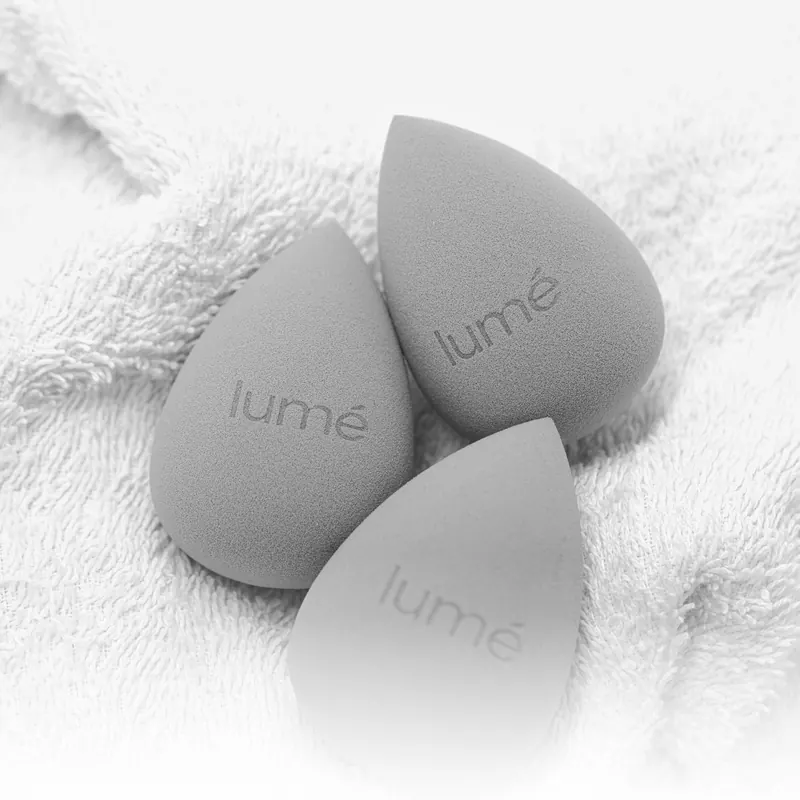 Tiga spons Lumécolors Beauty Blender abu-abu di atas handuk putih