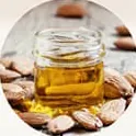 Minyak almond dalam toples kaca di antara kacang almond