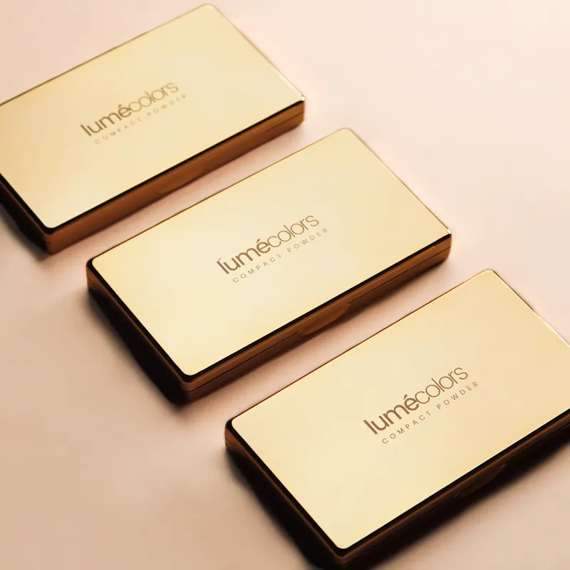 Tiga Lumécolors Compact Powder emas tertutup berjajar di atas latar pink