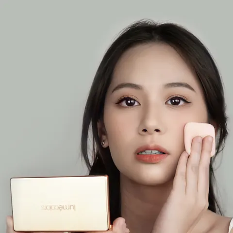 Model menepuk pipi dengan spons bedak sambil memegang Lumécolors Compact Powder