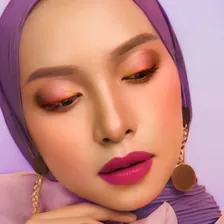 Model berhijab ungu dengan eyeshadow pink-oranye dan bibir magenta