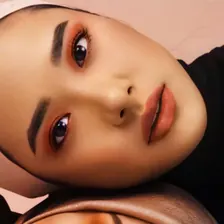 Model berhijab pink berbaring dengan eyeshadow oranye-merah