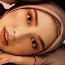 Model berhijab taupe berbaring dengan eyeshadow oranye