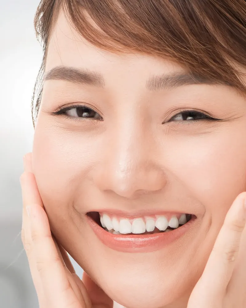 Perempuan tersenyum menepuk kedua pipi dengan telapak tangan