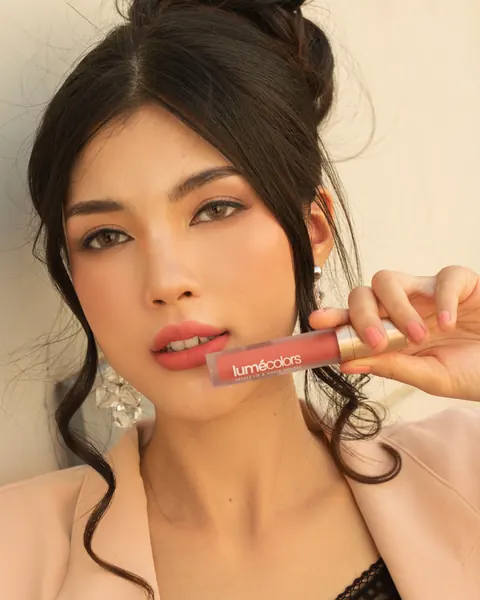 Model menempelkan tube Velvet Lip & Cheek Mousse ke bibirnya yang berwarna coral-nude