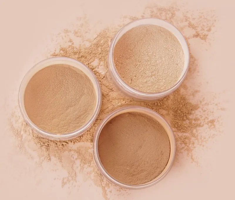 Tiga jar Loose Powder terbuka: shade Light Neutral, Medium Neutral dan Golden Tan dengan bubuk bertebaran