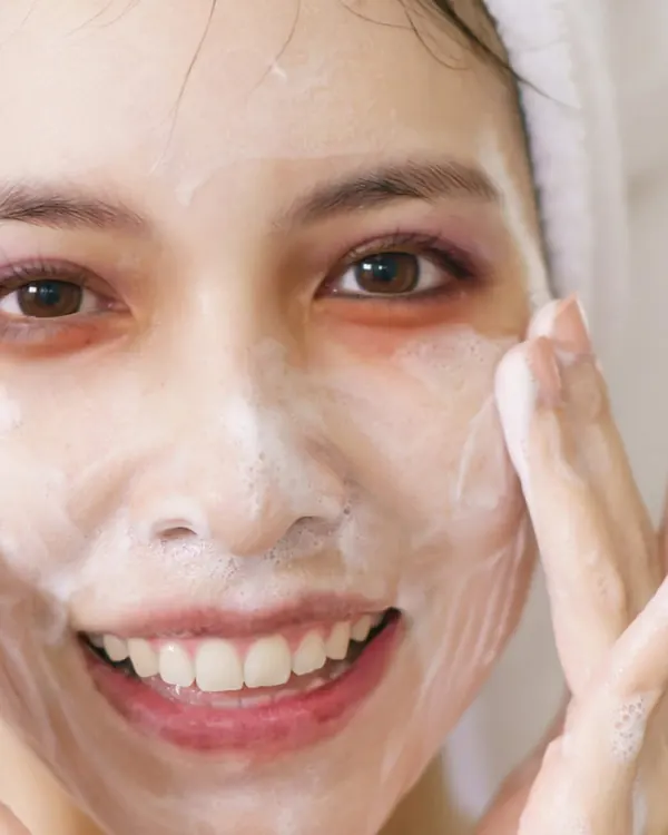 Wajah berbusa cleanser, kedua tangan di pipi
