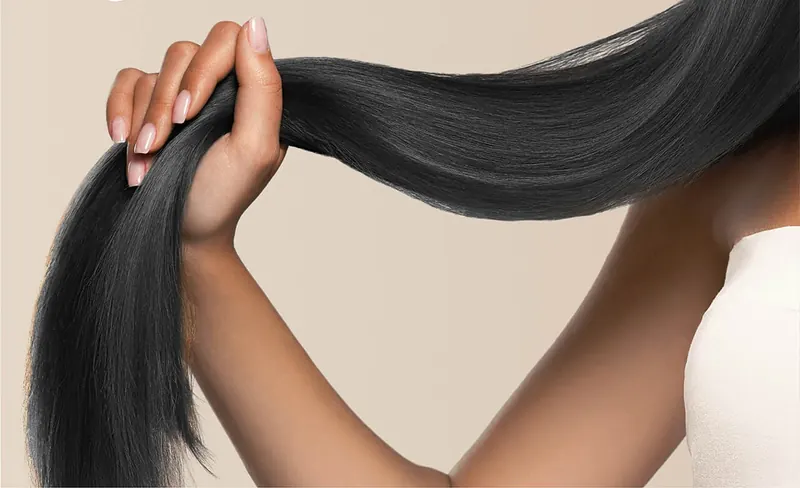 Tangan memegang rambut hitam panjang yang halus dan berkilau